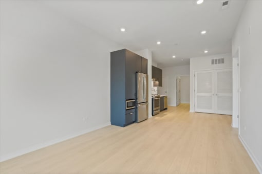 a renovated living room and kitchen with white walls and wood flooring