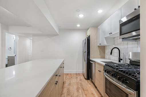 A modern kitchen with a white countertop and stainless steel appliances.