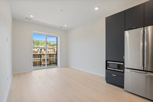 a living room with a refrigerator and a door to a balcony