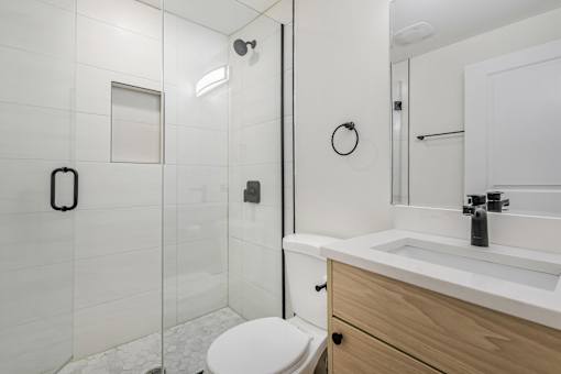 A white bathroom with a toilet, sink, and shower.