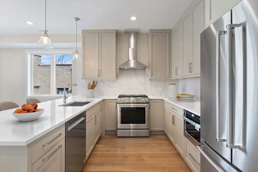 A modern kitchen with stainless steel appliances and wooden floors.