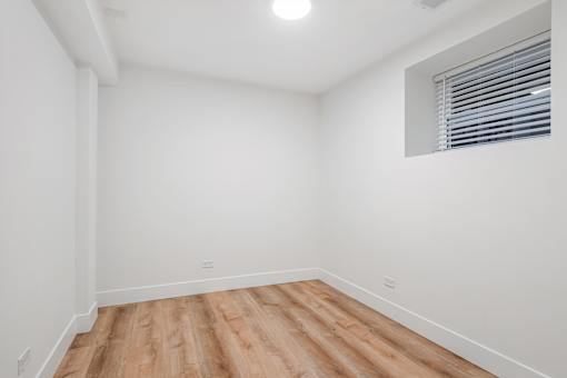 A room with wooden flooring and a window with blinds.