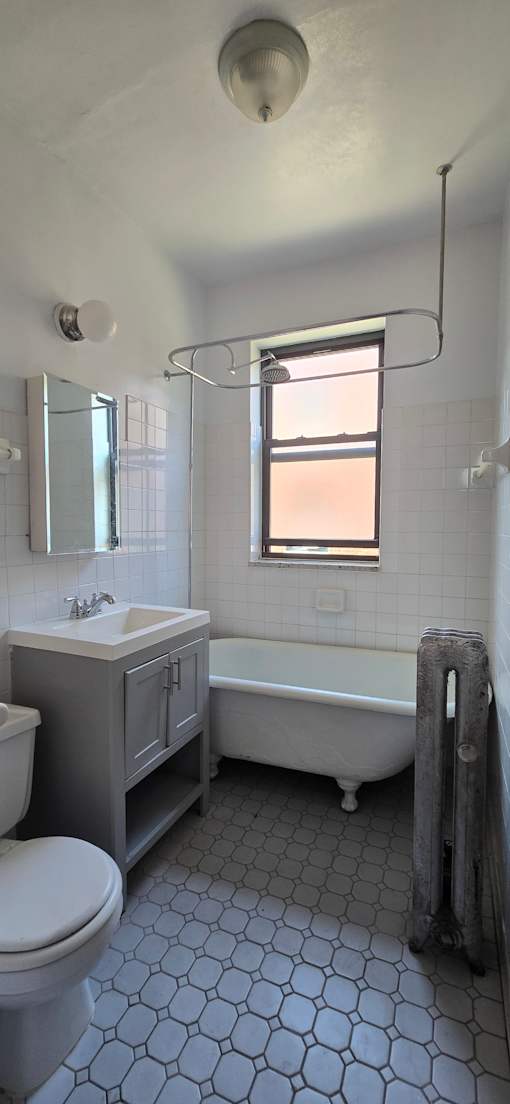 A white bathroom with a toilet, sink, and shower.