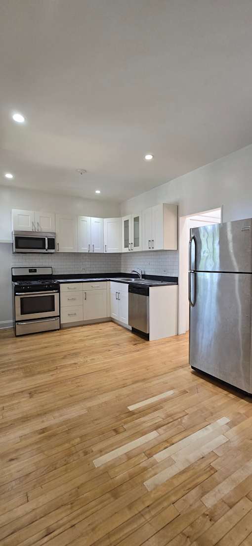 A kitchen with wooden floors and white walls.