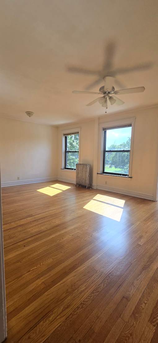 A room with a ceiling fan and wooden floors.