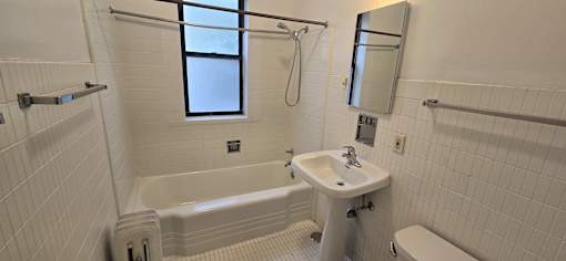 A white bathroom with a tub, sink, and toilet.