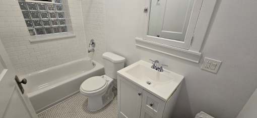 A white bathroom with a toilet, sink, and bathtub.