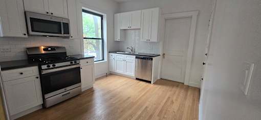 A kitchen with white cabinets and black countertops.