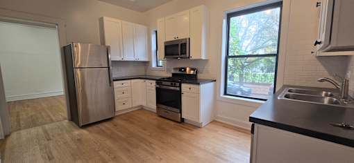 A kitchen with a stainless steel refrigerator and a window.