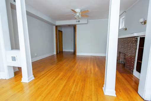 an empty living room with wood floors and a ceiling fan