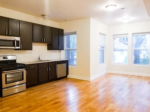 an empty kitchen with black cabinets and a wood floor