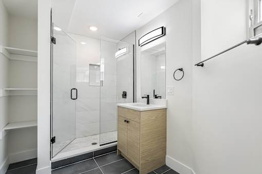 A modern bathroom with a walk-in shower and a wooden vanity.