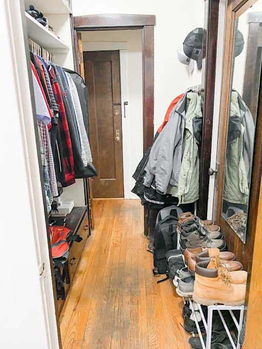 a walk in closet with a rack of shoes in it and a closet door open