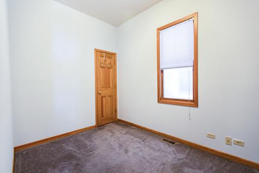 A room with a brown door and a window with blinds.