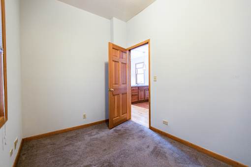 A room with a brown carpet and a wooden door.