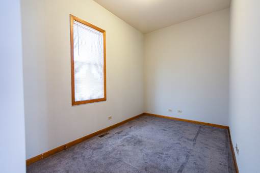 A room with a window and a carpeted floor.