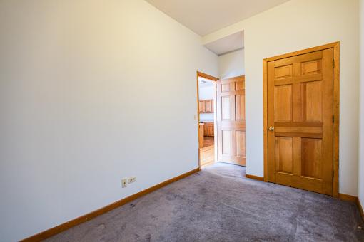 A room with a carpeted floor and a wooden door.