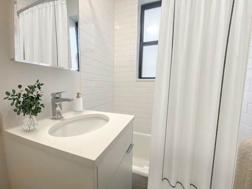 A white sink in a bathroom with a white curtain.