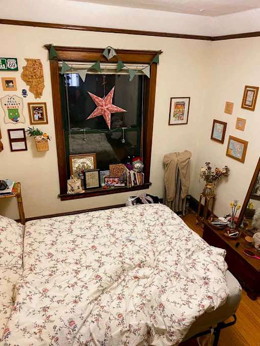 A bedroom with a floral bedspread and a mirror with a starfish decoration.