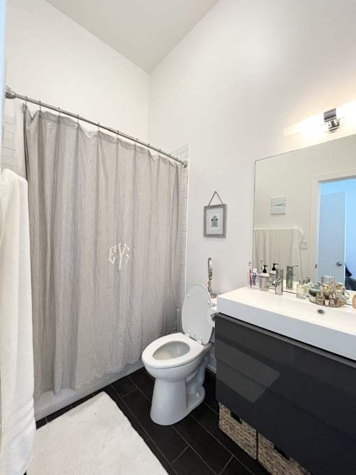 A bathroom with a toilet, sink, and shower curtain.