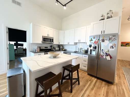 A kitchen with a white counter top and a fridge with magnets on it.