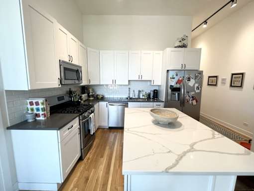 A kitchen with white cabinets and a marble counter top.