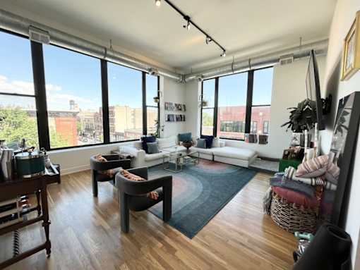 A living room with a white couch, a grey chair, and a wooden table.