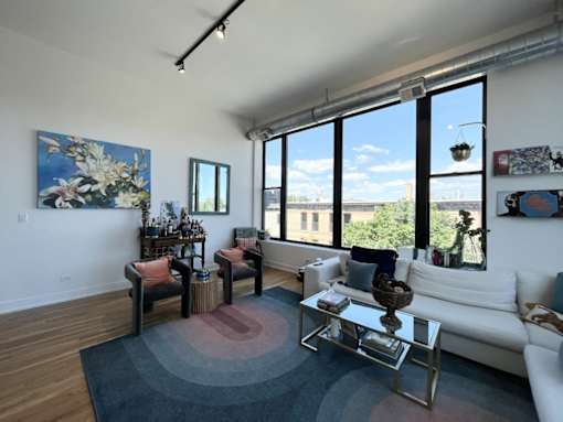 A living room with a white couch, a coffee table, and a large window.