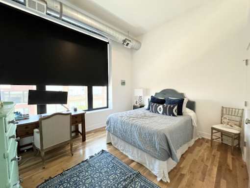 A bedroom with a bed, desk, chair, and window.