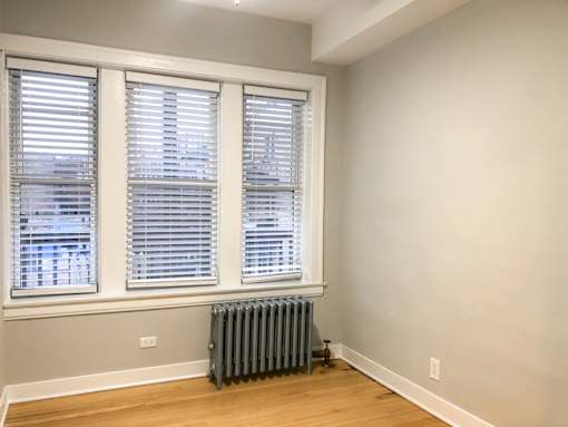 A room with a window and a radiator on the floor.
