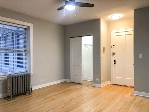 A room with a ceiling fan and a window with blinds.