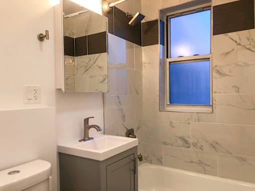 A bathroom with a marble tile wall and a window.