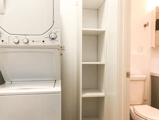 A white oven with a towel hanging on the handle is next to a white toilet.