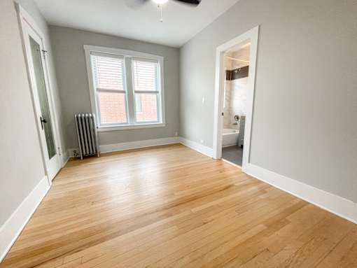 A room with wooden flooring and a window with blinds.