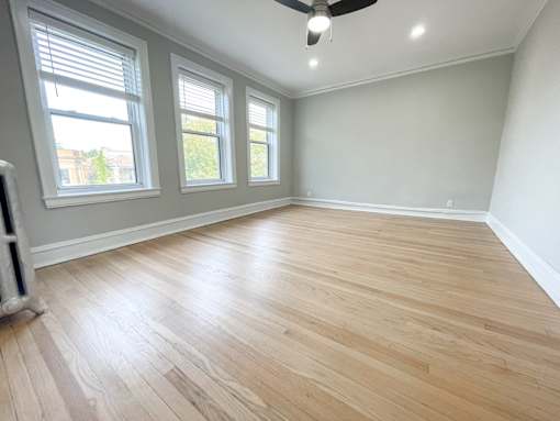 A room with wooden flooring and a ceiling fan.