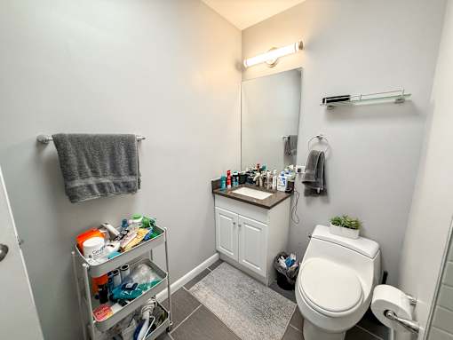 A bathroom with a toilet, sink, and a mirror.