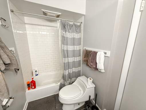 A white toilet in a bathroom with a shower curtain.