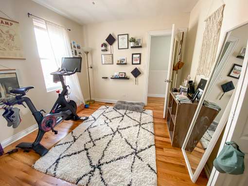 A room with a rug, a bike, a TV and a shelf.