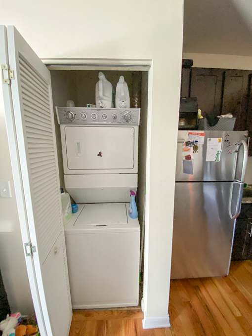 A white cabinet is open with a dishwasher and a washing machine inside.