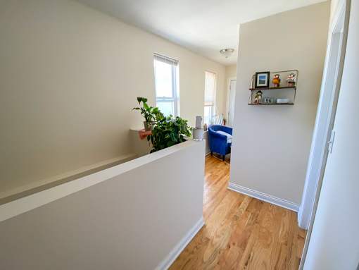 A room with a wooden floor and a white wall with a shelf on it.