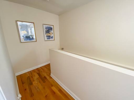 A room with wooden floors and two framed pictures on the wall.