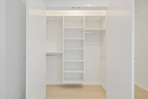a walk in closet with white shelving and empty shelves