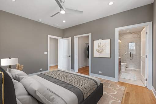 A bedroom with a large bed and a bathroom visible through the open door.