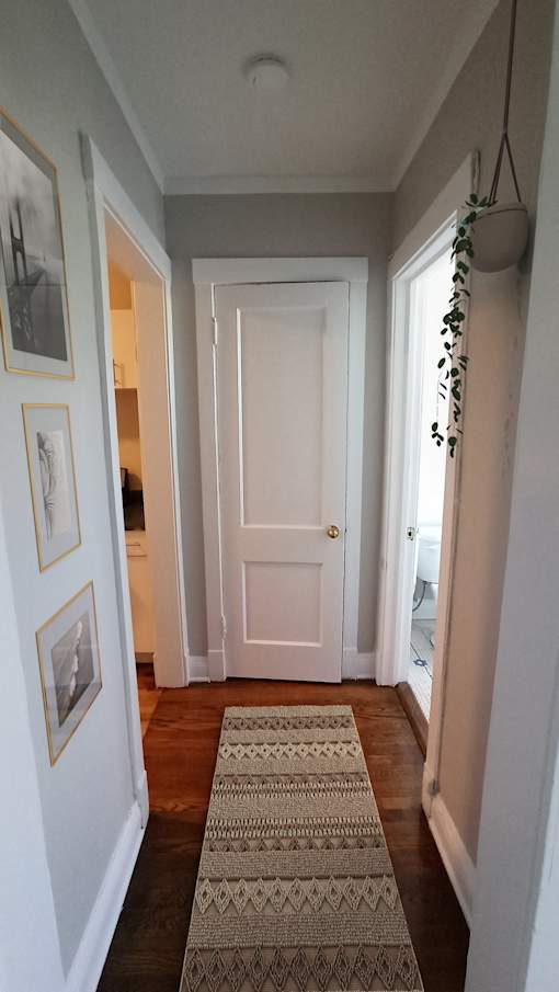 A hallway with a rug on the floor and pictures on the wall.
