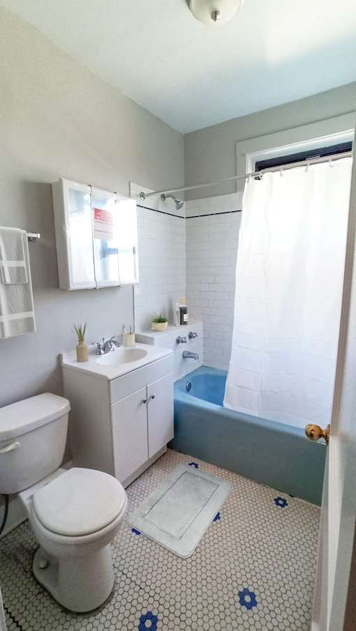 A white toilet sits in a bathroom with a blue and white tiled floor.