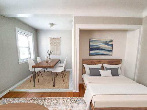 A bedroom with a bed, a table and chairs, and a painting on the wall.