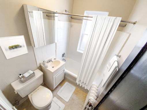 A white bathroom with a toilet, sink, and shower.