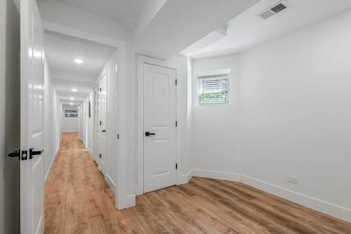 A long hallway with white walls and wooden floors.