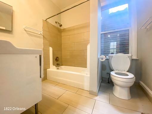 A white toilet is in a bathroom with a tub and a shower.