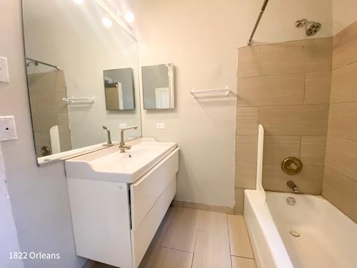 A white bathroom with a sink, mirror, and bathtub.